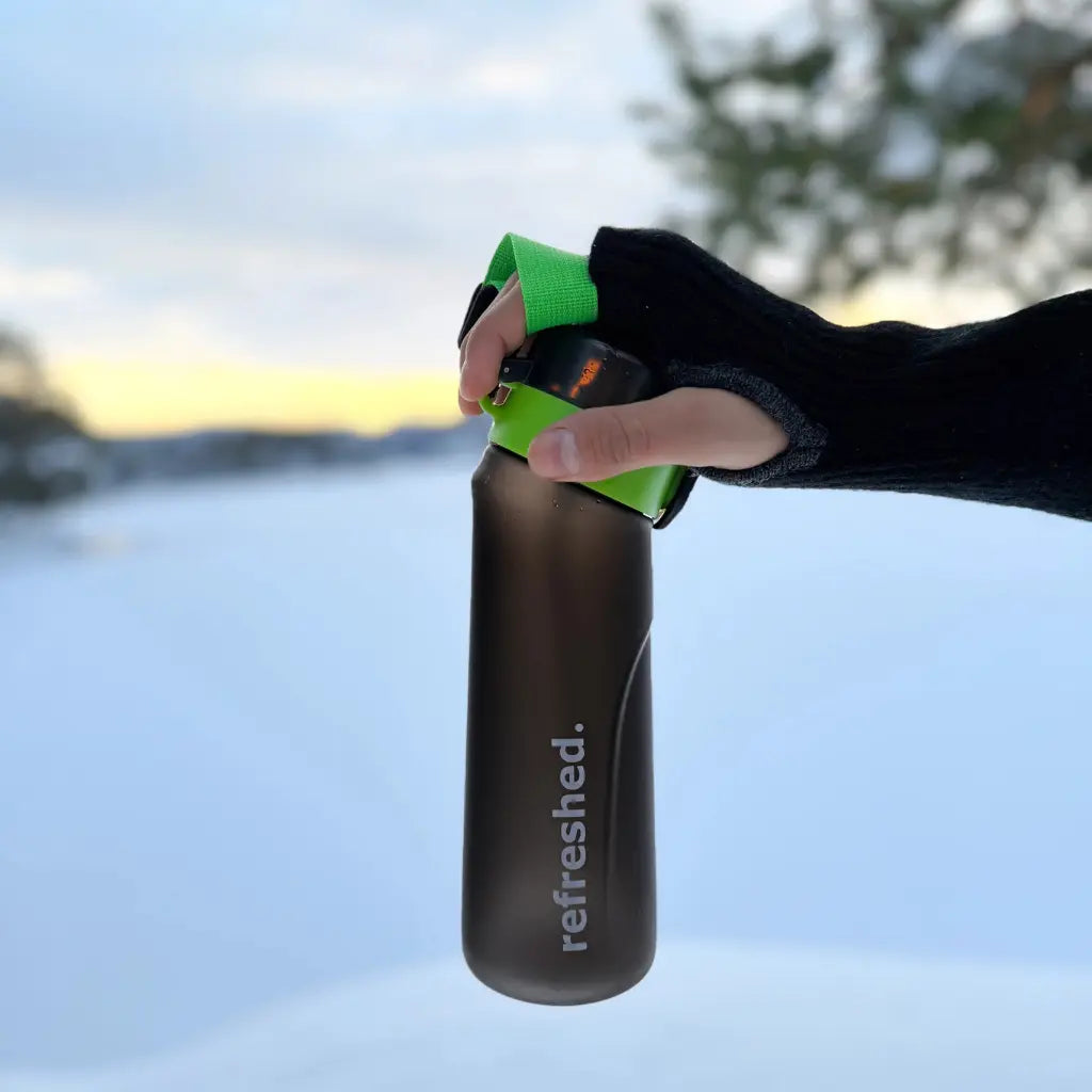 refreshed ignature flaske holdt av en person i vinterlandskap